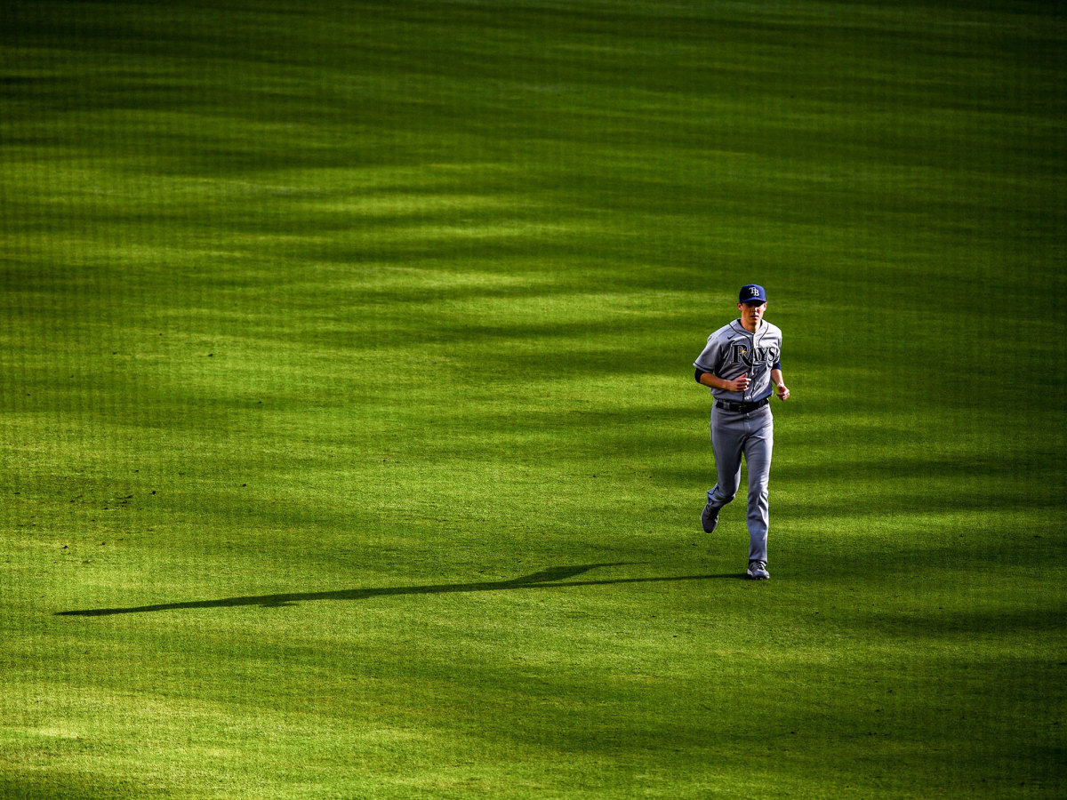 A Rays pitcher runs in the outfield